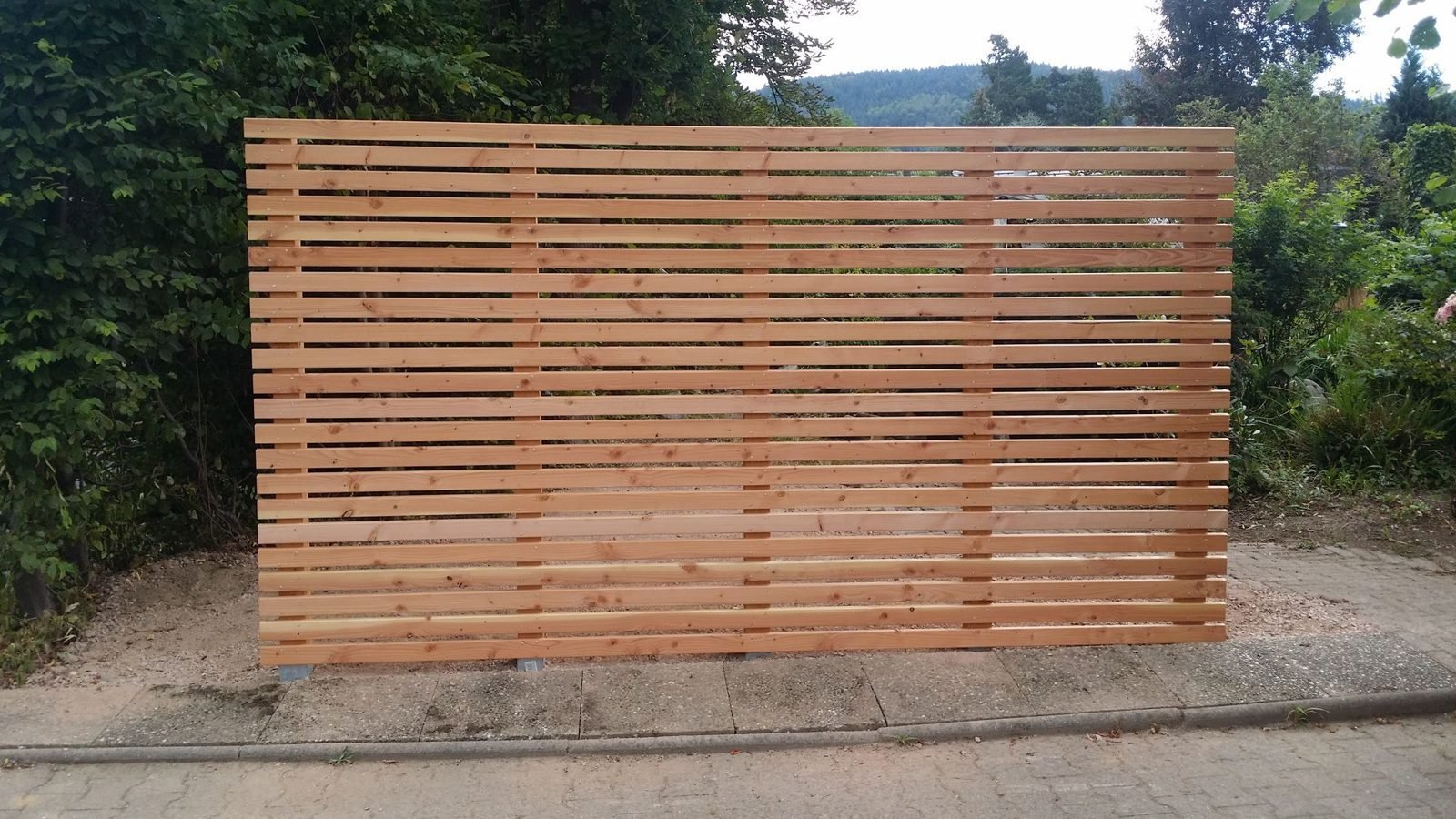 Sichtschutzwand aus waagerechten Holzlatten am Grundstücksrand